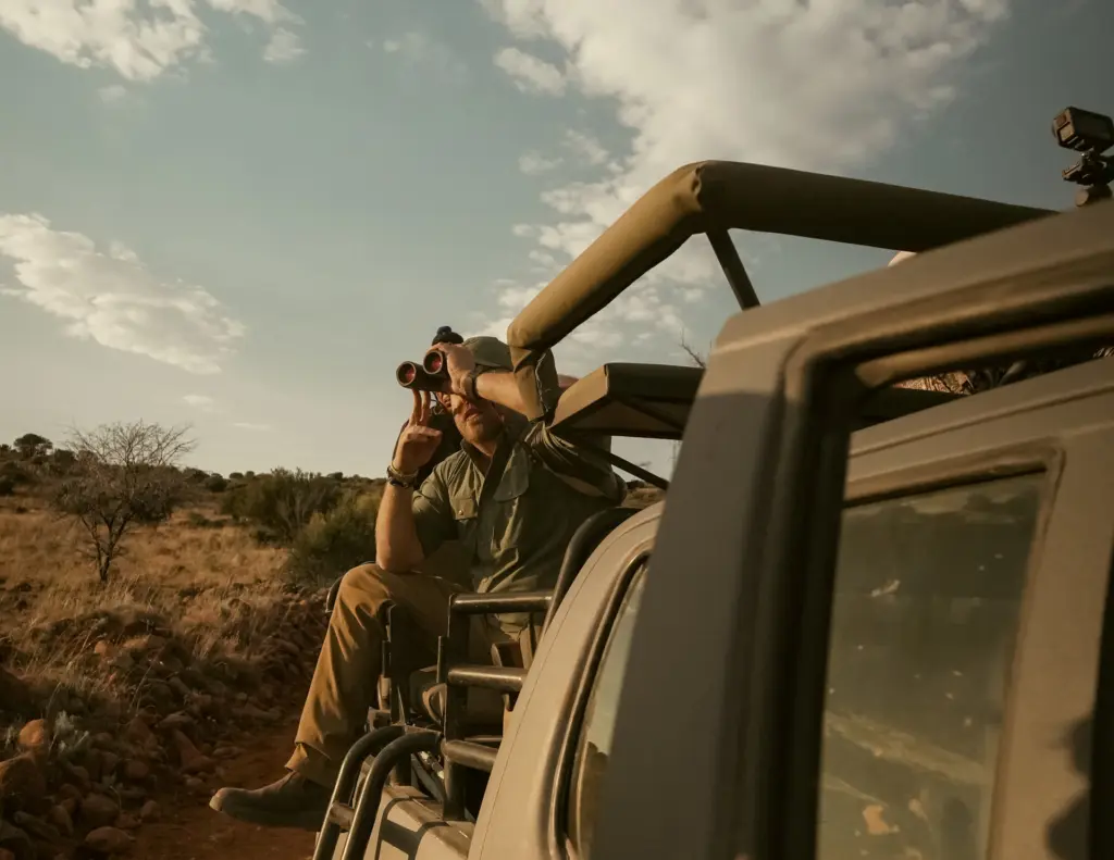 A hunter riding on the back of the safari truck in South Africa