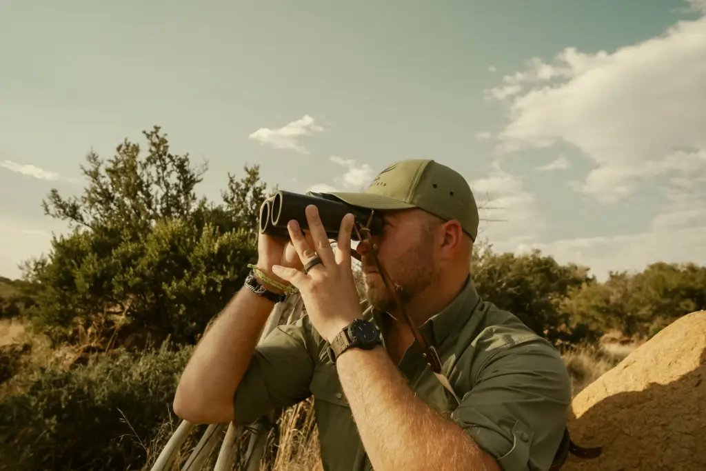 A guide glassing a hillside through binoculars in South Africa